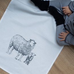 A gray and white tea towel featuring a detailed sketch of a sheep.