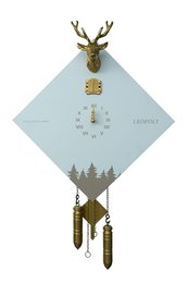 A traditional Black Forest cuckoo clock with a white and gold color scheme. The clock features a deer head design and a cuckoo bird that emerges from the clock face. The clock has a classic, rustic style that would complement a variety of home decor styles.