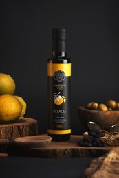 A bottle of fresh lemon-flavored olive oil with a splash of oil and a lemon slice. The bottle has a label with the product name and branding.