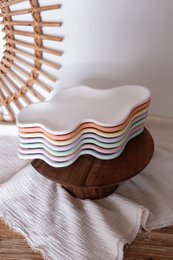  Decorative tray in various pastel colors including white, yellow, pink, lavender, orange, light blue, and light green. The tray has a wavy, organic shape with a wooden base.