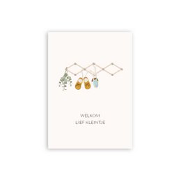 A6 card with the text "Welcome sweet little one" and an illustration of hanging baby items like pacifiers, rattles, and a mobile.