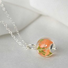 Delicate necklace with apricot glass flower charm. Handcrafted glass bead with floral design on a silver chain.