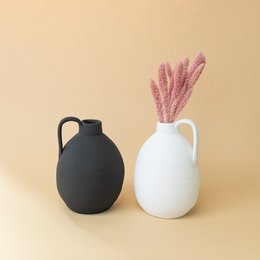 Tall, cylindrical white ceramic vase with a black ceramic vase.
