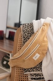 Tan shoulder bag with leopard print accent, featuring a zipper closure and a textured fabric design.