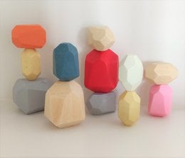 Colorful wooden stacking blocks in various geometric shapes, including cubes, rectangles, and triangles, in a variety of pastel and primary colors.