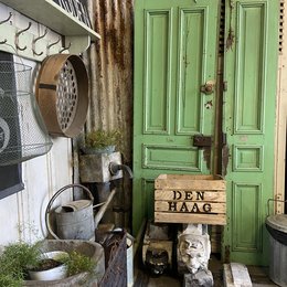 Rustic wooden storage box/crate with "Den Haag" text, featuring a vintage, distressed green door and other rustic decor elements.