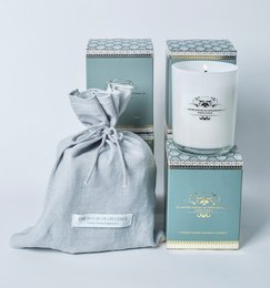 Serene Voyage, a scented candle with a tall, round shape, featuring a white wax and a gray and white patterned container. The candle is packaged in a gray fabric bag, adding to the serene and calming aesthetic.