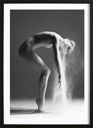 A black and white image of a dancer in a graceful pose, with dust or powder swirling around them.