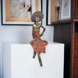 Bronze sculpture of a seated woman wearing a hat, available in various sizes and colors including blue, brown, green, red, turquoise, and gold.