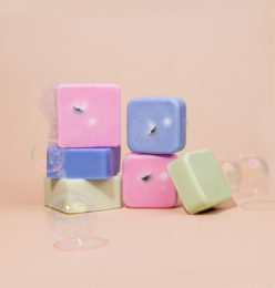 Colorful, square-shaped bath soaps in pastel shades of pink, blue, and green. The soaps appear to be soft and spongy in texture, suitable for use as kids' bath toys.