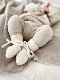 Soft, cozy off-white merino wool baby booties with laces and ribbed cuffs.