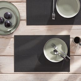 Rectangular black placemat with a textured surface, suitable for use on a dining table.