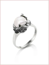  A silver signet ring featuring a large pearl-like stone set in an ornate, floral-inspired design.
