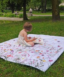 Floral picnic blanket in a backpack, featuring a colorful pattern of various flowers and plants. Ideal for outdoor gatherings and relaxation in nature.