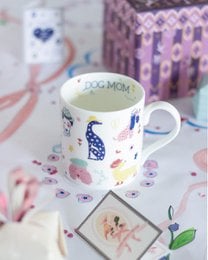 "White ceramic mug with dog mom text, colorful dog illustrations, hearts, flowers, and playful design"