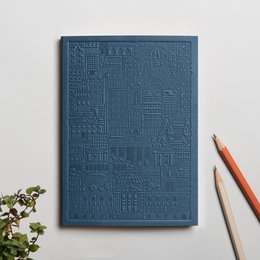 A hardcover notebook with an embossed geometric pattern in various shades of green, including blue-green, olive, and mint. The notebook has a minimalist, modern design.