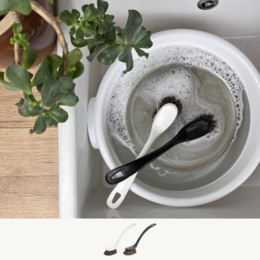 A white dishwash brush with a black handle, suitable for cleaning dishes and kitchenware.