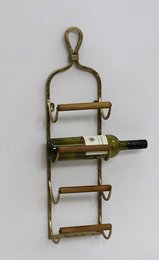 A gold-colored metal and wood wine rack with three shelves for storing wine bottles.