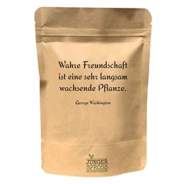 A round, tall paprika-colored candle with a quote about true friendship being a growing plant.