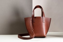 Cognac, black, and clay colored leather handbag with a structured tote shape and adjustable shoulder strap.