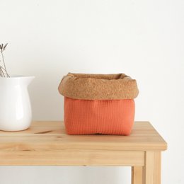 Terracotta basket with orange fabric lining and natural fiber trim. Suitable for storage and organization in the home.