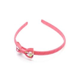 A pink headband with a small bow and a heart-shaped charm in a red and white Liberty Betsy print pattern. Suitable for children.