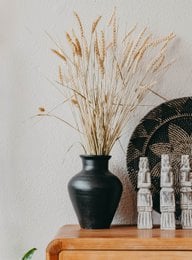 Dried natural wheat stalks in a black vase, decorative item for home.