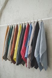 Linen kitchen towels in various colors including forest green, moss green, dark green, rust, mustard, white, off-white, natural, black stripes, gray checks, graphite gray, charcoal gray, black, pale dogwood, dusty purple, frozen cranberry, lavender, glacier gray, and dusk blue. The towels are soft, absorbent, and measure approximately 50x70 cm or 19.7x27.6 inches.