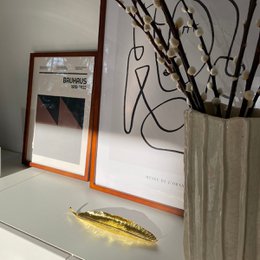 Gold-colored, leaf-shaped incense holder measuring 25 x 5 cm.