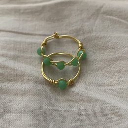 Elegant gold-tone statement ring with green crystal accents. Unique design with a modern, minimalist aesthetic. Suitable for everyday wear or special occasions.