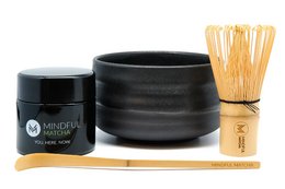 Mindful Matcha Set - Bio. Includes a black ceramic matcha bowl, a bamboo whisk, and a tin of organic matcha powder. Perfect for preparing and enjoying traditional Japanese matcha tea.