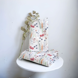 Soft, cozy swaddle blanket with a floral and nature-inspired print in colors of sand, blue, and forest green. Suitable for newborns and infants.