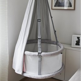 A classic white crib with a round, elevated design and adjustable straps for safety and convenience.