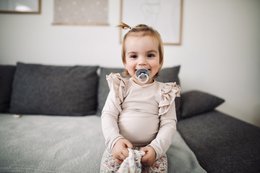 Beige bodysuit with ruffles for infants, available in sizes newborn to 18 months.