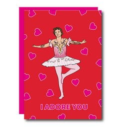 A Valentine's Day card featuring a ballerina in a pink tutu surrounded by heart shapes on a red background. The text on the card reads "I ADORE YOU".