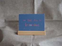 A greeting card with the text "A kiss through the letterbox" written on it, surrounded by a decorative plant and other home decor items.