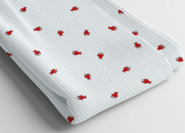  A soft, cotton baby blanket with a repeating pattern of small, red ladybug designs.