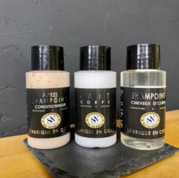 Hotel toiletry set including shampoo, conditioner, and body milk in black, white, and silver packaging.