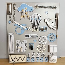 A busy board with various interactive elements like buttons, switches, and shapes for toddlers to explore and play with. The board features a variety of colors, textures, and shapes that can stimulate a child's senses and encourage fine motor skills development.