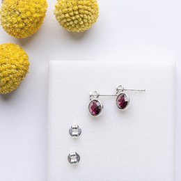 Oval-shaped purple gemstone stud earrings with silver metal settings.