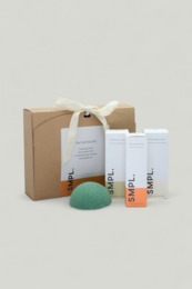 Skincare gift set with white bottles, green soap, kraft paper packaging, spa beauty kit with ribbon bow.