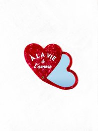 Red heart-shaped makeup mirror with "A la vie" text. Decorative heart-shaped design.