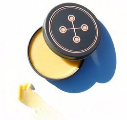 Natural multipurpose balm in a round black container with a graphic design.