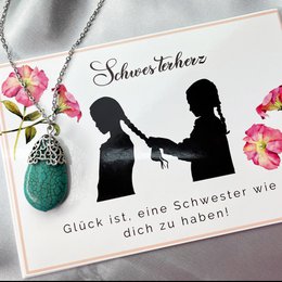 A greeting card featuring the silhouettes of two women with the text "Schwesterherz" (Sister's Heart) and "Glück ist, eine Schwester wie dich zu haben!" (Happiness is having a sister like you!). The card is decorated with pink and white flowers.