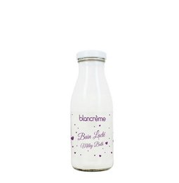 A clear glass bottle containing a white, creamy liquid labeled "Milk bath - Milk". The bottle has a silver metal lid.