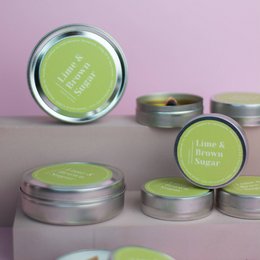 Lime and brown sugar scented soy candles in round tin containers.
