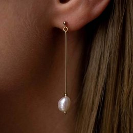 Long, dangling pearl earrings with a simple, elegant design.