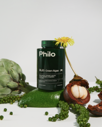 Green and yellow supplement container with fresh produce, including a flower, leaves, and a fruit.