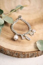 Charm bracelet with silver beads, charms, and a pearl pendant.