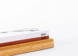 A sharpening set with a double-sided 2000/6000 grit whetstone, anti-slip bamboo base, flattening stone, and 15-degree angle guide for precise knife sharpening.